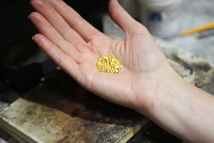When creating a Fairtrade Gold wedding ring by hand, the first step is to weigh out the 24K gold grain to be used in the ring.